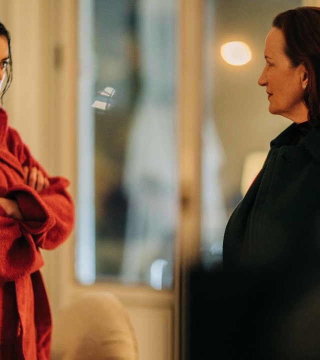 "Survivors - Die Rückkehr":  Léa (Adèle Wismes, l.), steht in ihrer Wohnung Bianca (Maddalena Crippa, r.), der Noch-Ehefrau ihres verstorbenen Lebensgefährten Armado, mit verschränkten Armen und feindselig blickend, gegenüber.
