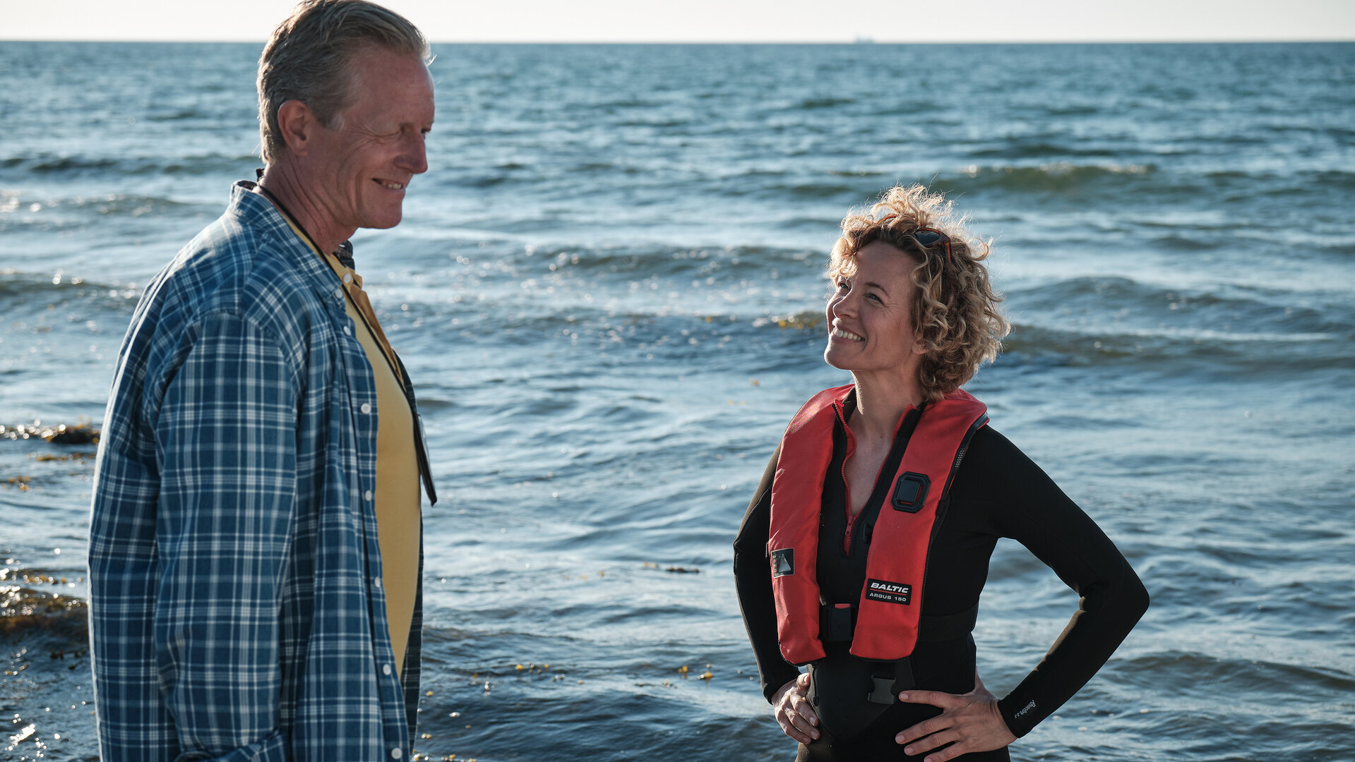 "Dan Sommerdahl - Tödliche Idylle: Das Cannes des Nordens": Dan Sommerdahl (Peter Mygind) und Josefine (Maibritt Saerens) stehen sich gegenüber und lächeln sich an. Im Hintergrund ist das Meer zu sehen.