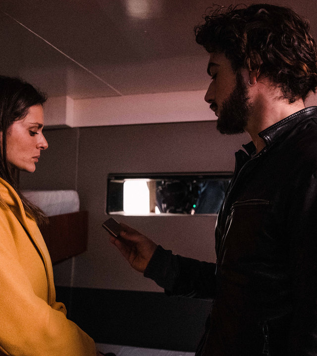 "Survivors - Mörder": Lorenzo (Giacomo Giorgio) steht Paola (Raffaella Rea) in ihrer Kabine auf dem Segelschiff gegenüber. Er sieht sie intensiv an, während sie unsicher nach unten blickt.