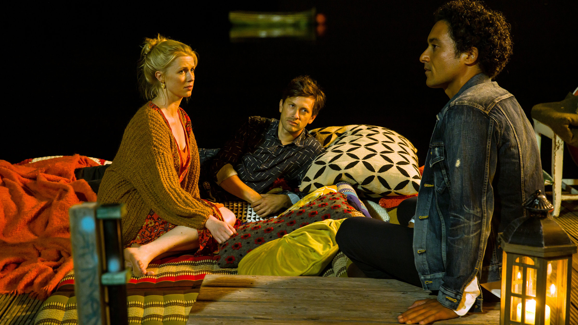 "Matze, Kebab und Sauerkraut": Charlotte (Christine Eixenberger), Noah (Franz Dinda) und Hakim (Omar El-Saeidi) sitzen nachts gemütlich auf Charlottes Hausboot. Charlotte trägt eine Strickjacke und ist barfuß. Noah liegt neben ihr auf einem Kissen und Hakim sitzt etwas abseits und sieht nachdenklich aus.