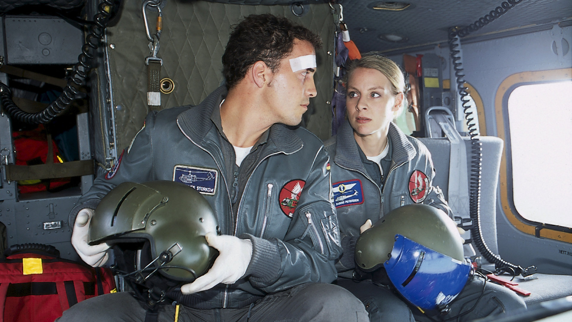 "Die Rettungsflieger - Fahrerflucht": Sabine (Marlene Marlow) und Jonny (Patrick Wolff) sitzen nebeneinander im Hubschrauber und schauen sich an. Auf Jonnys Stirn klebt ein Pflaster.