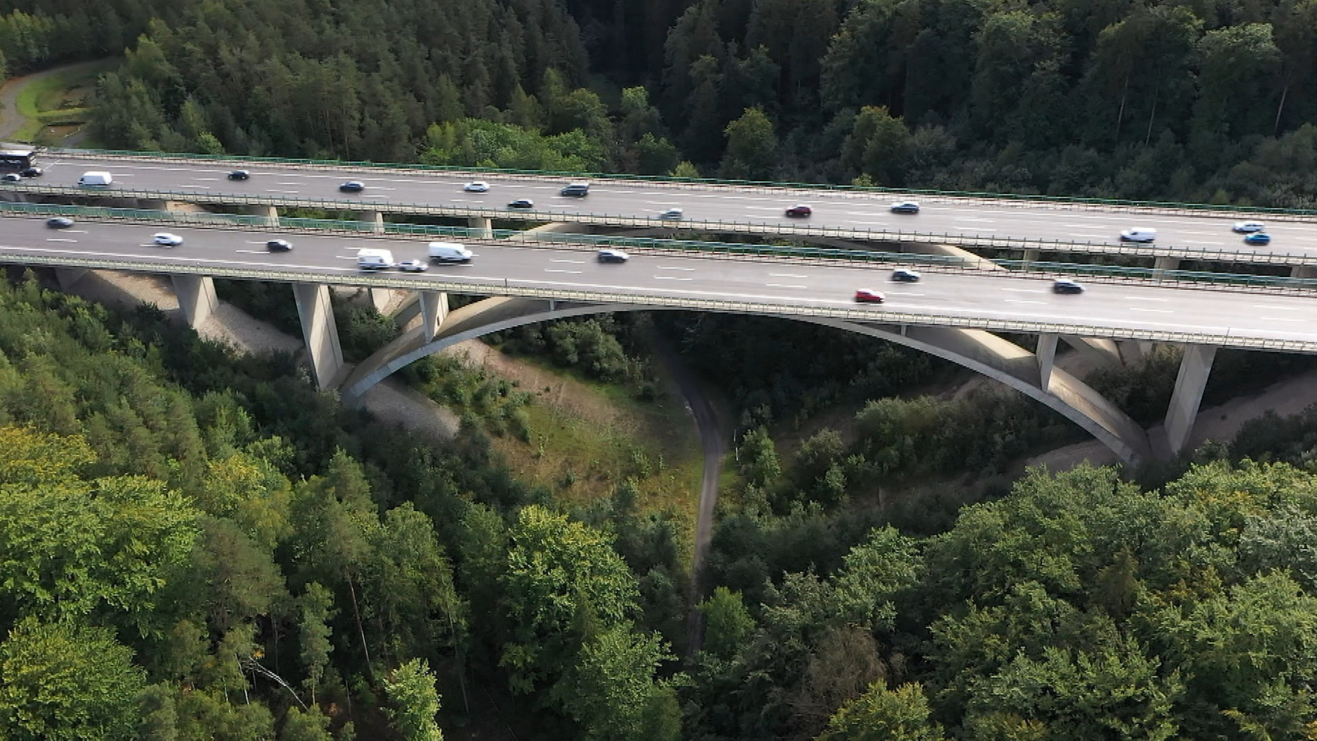 "hallo deutschland: Mord an der Teufelstalbrücke": Eine Autobahnbrücke mit zwei Fahrbahnabschnitten und jeweils drei Fahrspuren führt über ein Waldstück. Unter der Brücke ein Waldweg. Die Luftaufnahme zeigt Verkehr auf allen Fahrspuren.