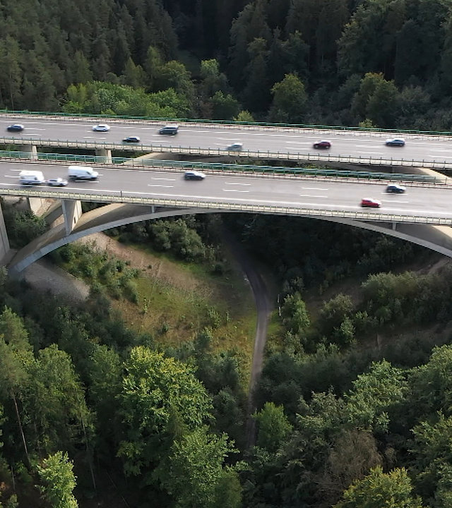 "hallo deutschland: Mord an der Teufelstalbrücke": Eine Autobahnbrücke mit zwei Fahrbahnabschnitten und jeweils drei Fahrspuren führt über ein Waldstück. Unter der Brücke ein Waldweg. Die Luftaufnahme zeigt Verkehr auf allen Fahrspuren.