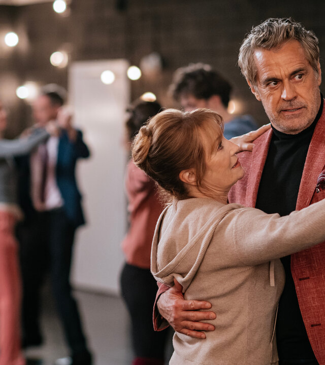 "Harry Wild - Mörderjagd in Dublin: Tanz mit dem Tod": Harry Wild (Jane Seymour) und Marcello (Edoardo Costa) tanzen in der Tanzschule miteinander. Der Raum ist dunkel, viele kleine Lampen spenden Licht. Im Hintergrund, nur verschwommen zu erkennen, tanzen drei weitere Paare.