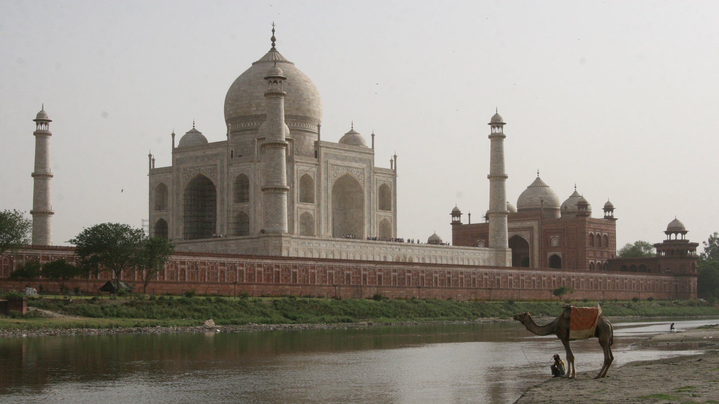 "Weltwunder, die schönsten Plätze der Erde": Der weiße Taj Mahal-Palast, davor der Yamuna-Fluss, an dem ein Mann mit seinem Kamel Pause macht.