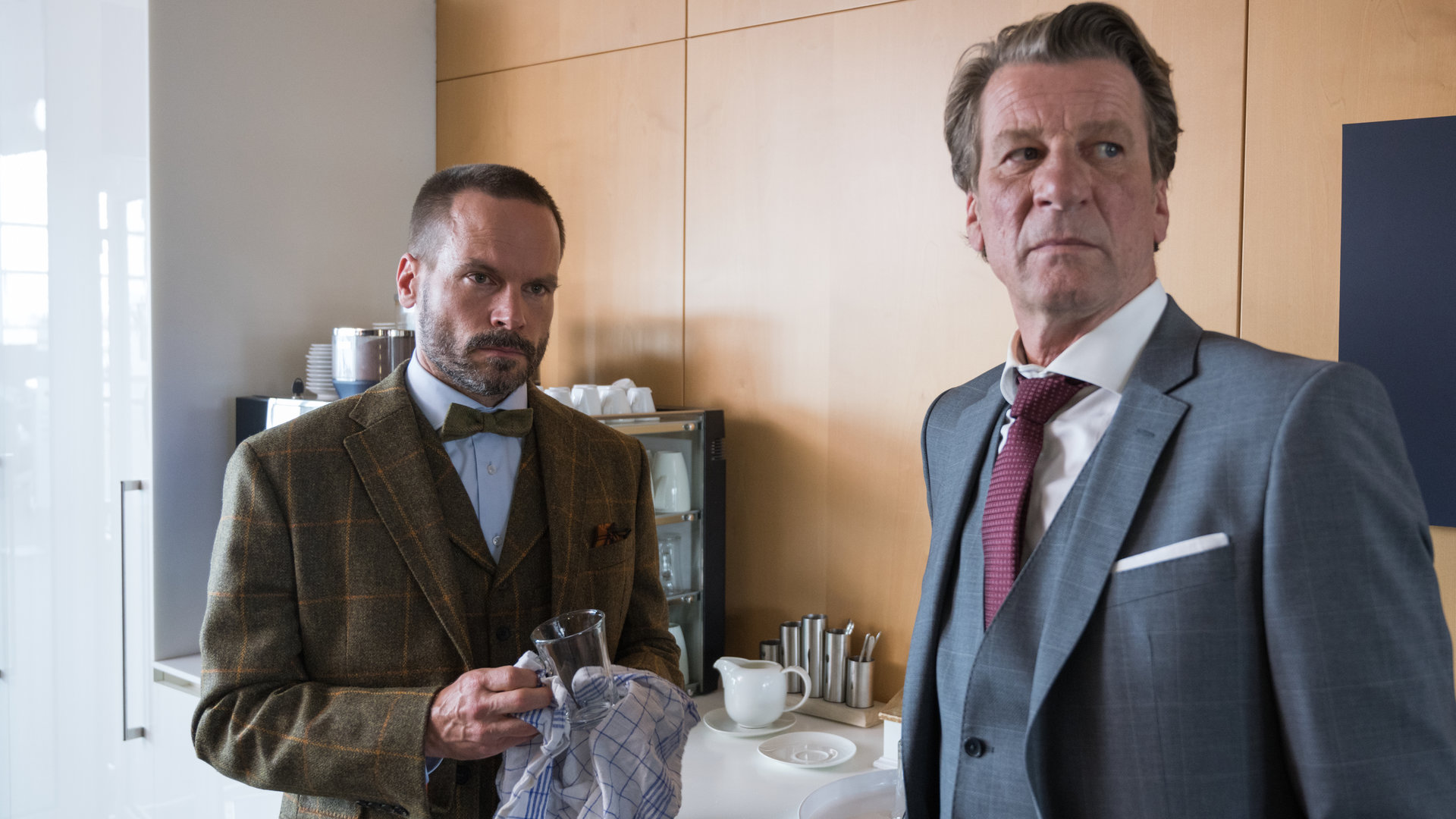 "Ein Fall für zwei - Advokaten und Mörder": Leo Oswald (Wanja Mues) und Burkhard Westmann (Michael von Au) stehen in einer Küche. Leo Oswald trocknet ein Glas ab. Beide schauen in die selbe Richtung.