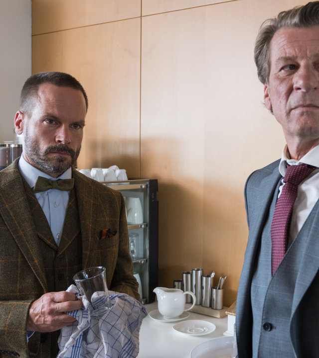 "Ein Fall für zwei - Advokaten und Mörder": Leo Oswald (Wanja Mues) und Burkhard Westmann (Michael von Au) stehen in einer Küche. Leo Oswald trocknet ein Glas ab. Beide schauen in die selbe Richtung.