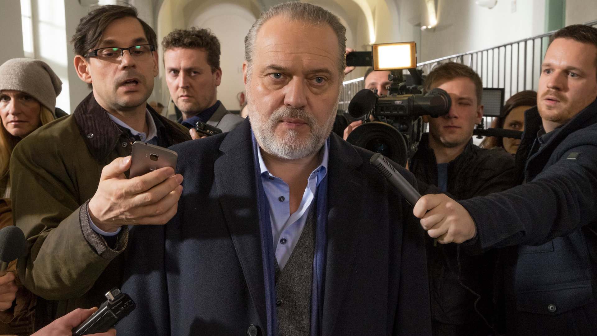 "Der Alte - Heimattreu": Richard Voss (Jan-Gregor Kremp) wird von einer Gruppe Reporter umzingelt, die ihm Aufnahmemikrofone entgegenstrecken und eine Fernsehkamera auf ihn richten. Voss blickt entnervt drein.