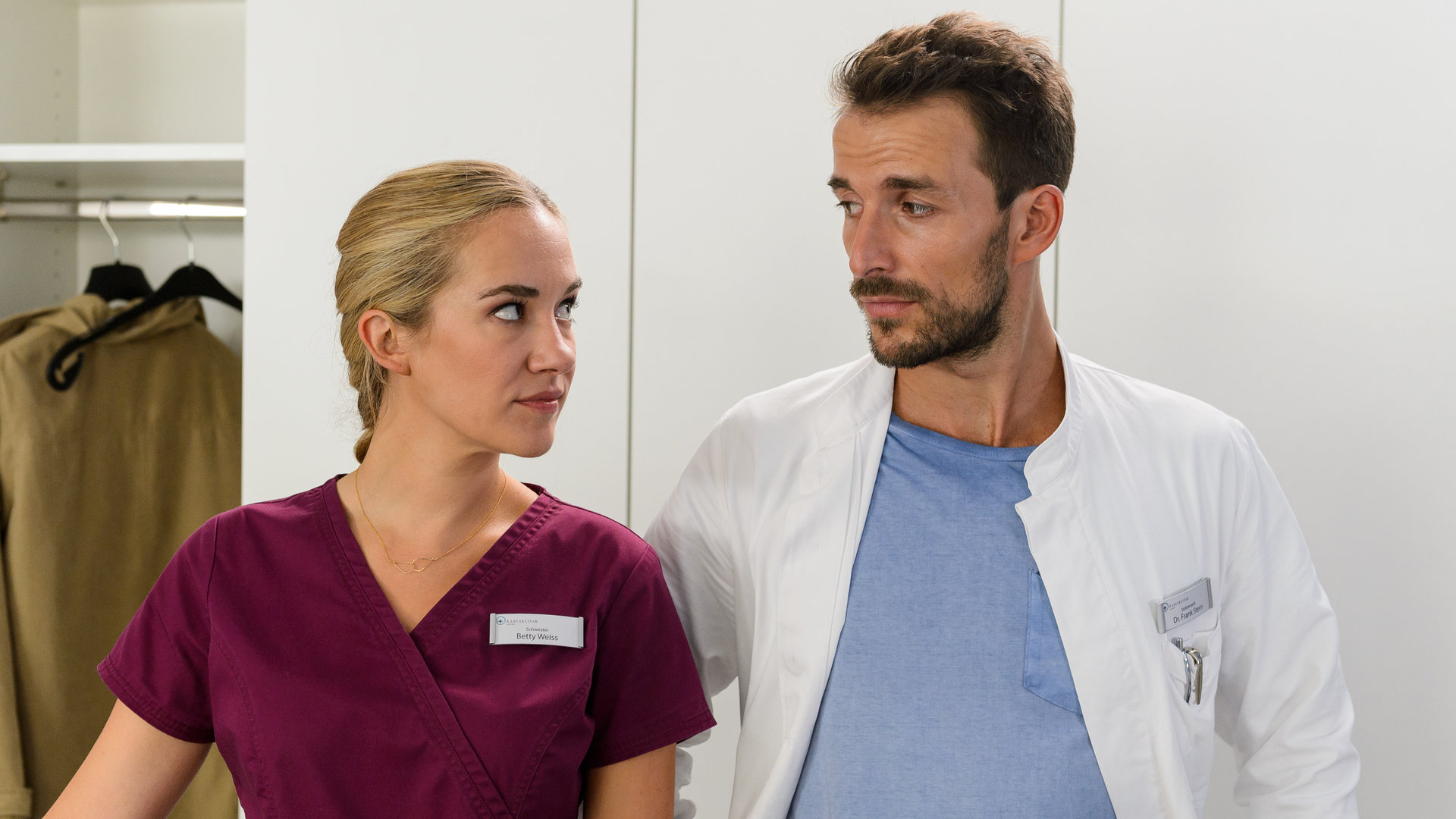 "Bettys Diagnose - Zweite Chance": Betty Weiss (Annina Hellenthal) schaut Dr. Frank Stern (Max Alberti), der neben ihr in einem Zimmer steht, sehr skeptisch an.