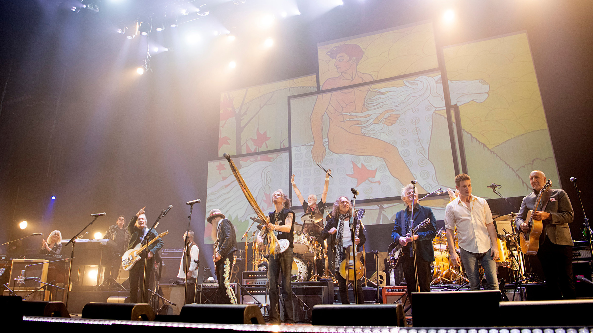 "Mick Fleetwood & Friends": Mehrere Musiker stehen nebeneinander auf einer Bühne vor einer Videowall. Zum Teil halten sie Instrumente in den Händen. Vor ihnen stehen Mikrofone.