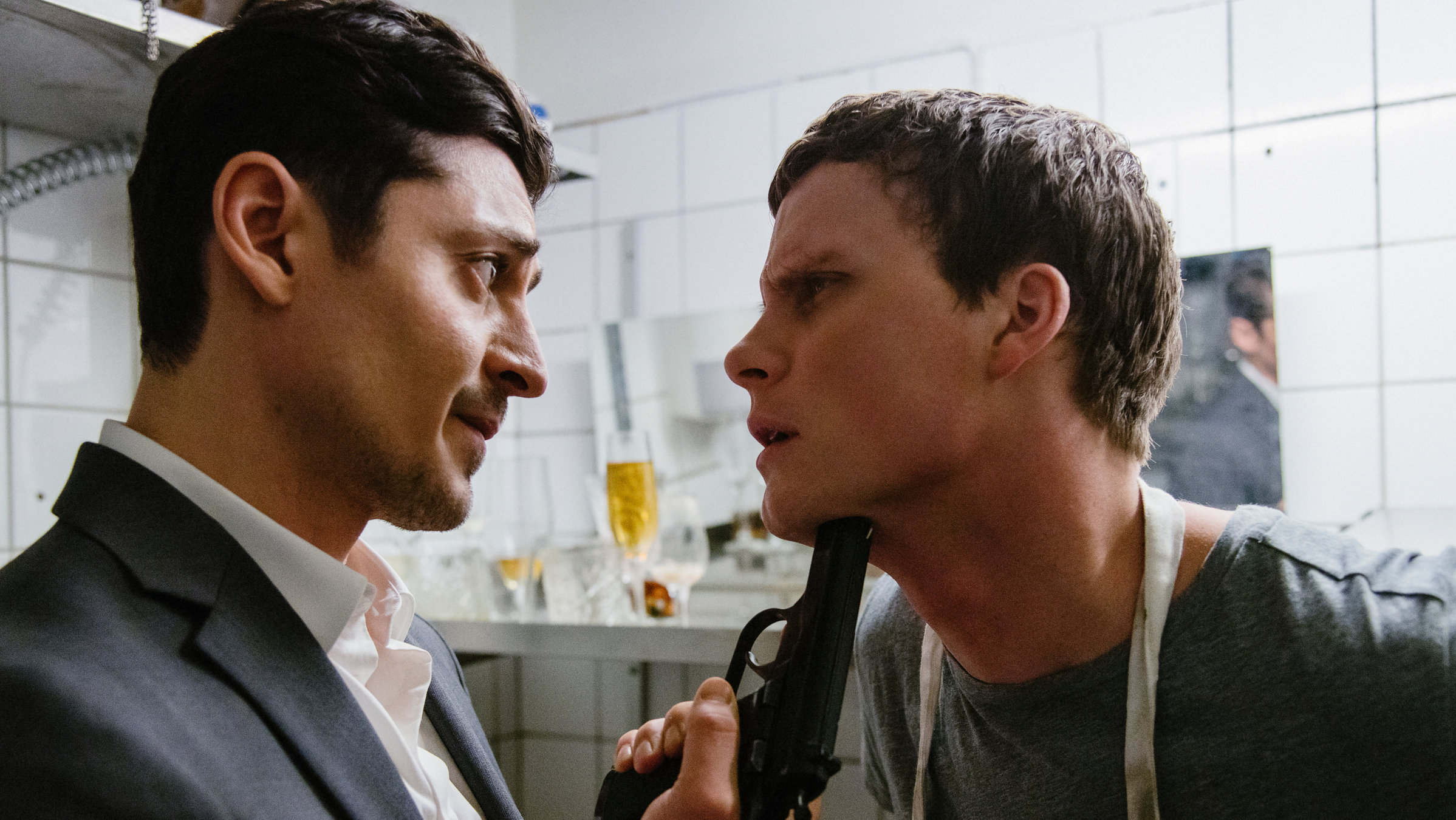 "Hanna Svensson - Blutsbande": Davor Mimica (Alexej Manvelov) steht in der Küche seines Restaurants dicht vor Christian (Adam Pålsson) und hält ihm drohend eine Waffe unters Kinn.