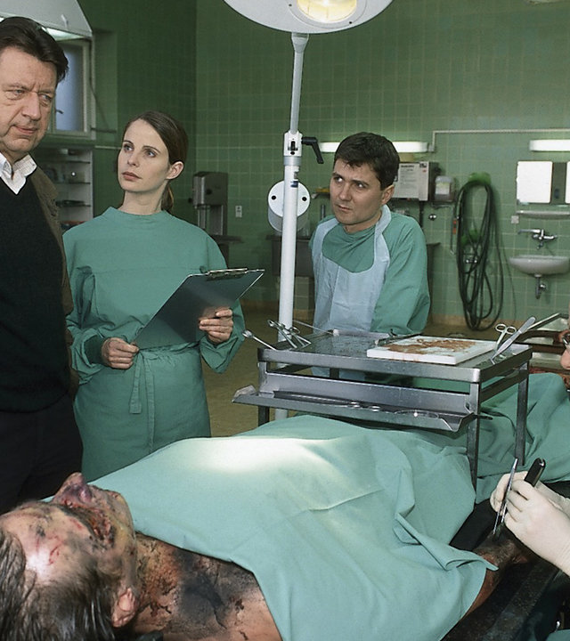 "Der letzte Zeuge - Der Fluch des letzten Königs": Gerichtsmediziner Dr. Robert Kolmaar (Ulrich Mühe), Dr. Leilah Berg (Julia Jäger) und Fred Schröder (Volker Ranisch) berichten Joe Hoffer (Jörg Gudzuhn) über ihre ersten Untersuchungsergebnisse. Sie befinden sich im Obduktionssaal.