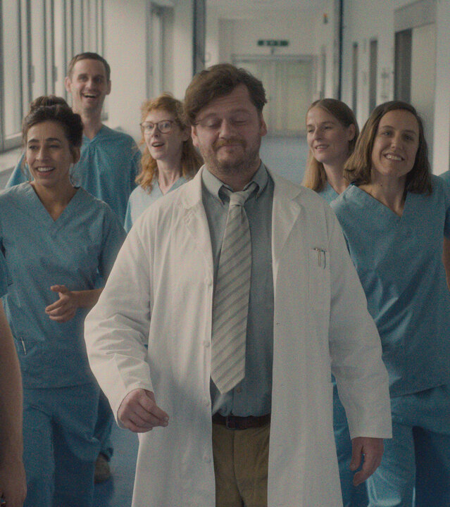 "Das Manko - Schönen Tag noch , ihr Lachse!": Das Manko läuft in Klinikklamotten durch die Station: Romantik Manko (Jan Krauter), Horror Manko (Carol Schuler), Perplex Manko (Sebastian Grünewald), Panik Manko (Sarah Bauerett), Wichtig Manko (David Simon), Mauerblümchen Manko (Julia Schubert), Bienchen Manko (Annika Meier), Dumm Manko (Jonas Hien), Gute Laune Manko (Bastian Reiber). Alle schauen freudig oder lachend nach vorn.