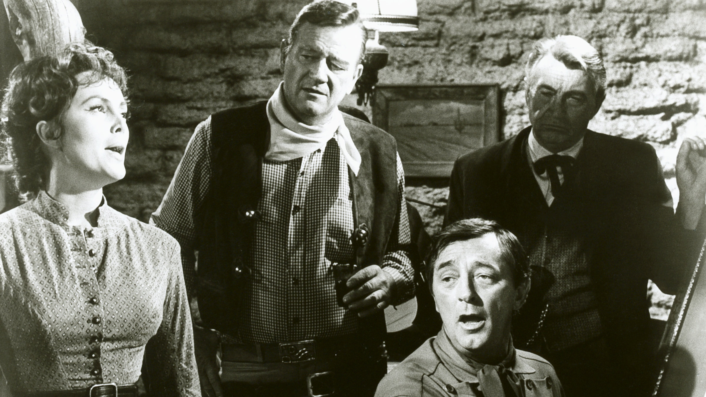 "El Dorado" - In El Dorado ist man nicht sehr begeistert, als ein alternder Revolverheld namens Cole Thornton (John Wayne, 2.v.l.) auftaucht. Er ist ein alter Freund von Sheriffs Harrah (Robert Mitchum, sitzend), aber er kam nicht, um Harrah zu besuchen. Rancher Kewan Mac Donald (R.G. Armstrong, r.) und seine Tochter Joe (Michele Carey, l.) haben Grund zur Skepsis.