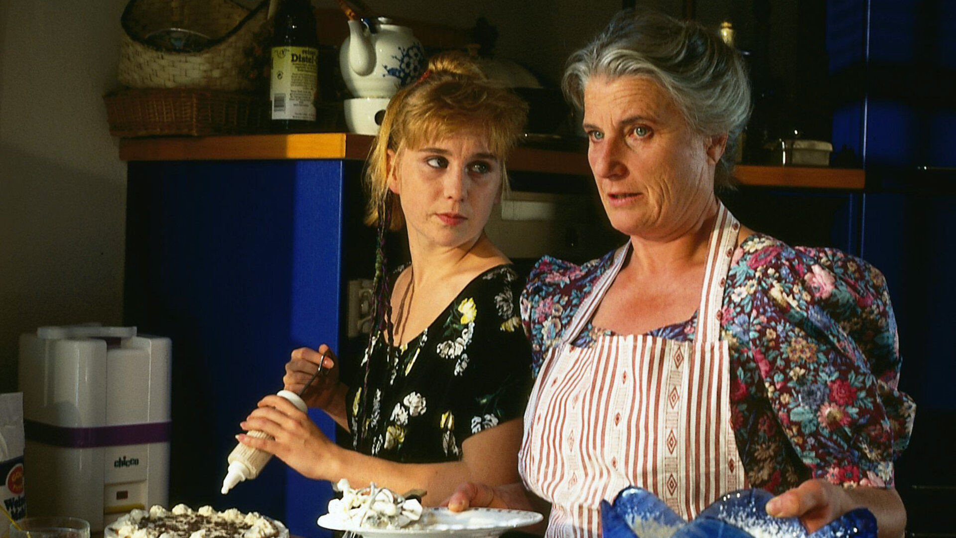 "Alle meine Töchter - Disharmonie": Elsa Fischer (Luise Deschauer) und Sina (Nadine Neumann) stehen in der Küche, während Sina eine Torte dekoriert und Anweisungen von Elsa bekommt.