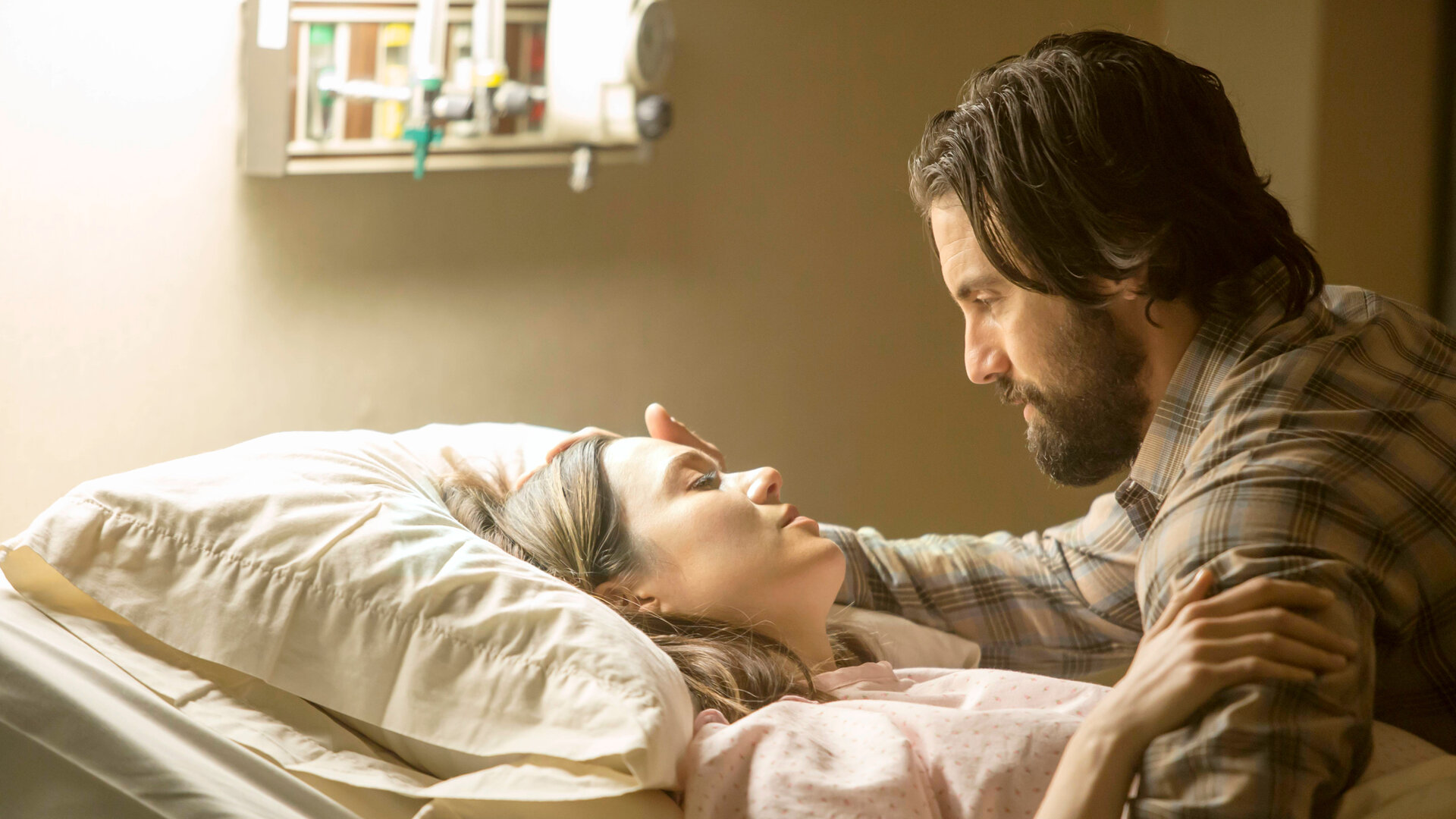 "This Is Us - Das ist Leben: Happy Birthday": Rebecca Pearson (Mandy Moore) liegt in einem Krankenhausbett und trägt ein Operationshemd. Jack Pearson (Milo Ventimiglia) sitzt bei ihr und legt ihr sanft eine Hand ans Gesicht. Beide blicken sich tief in die Augen.