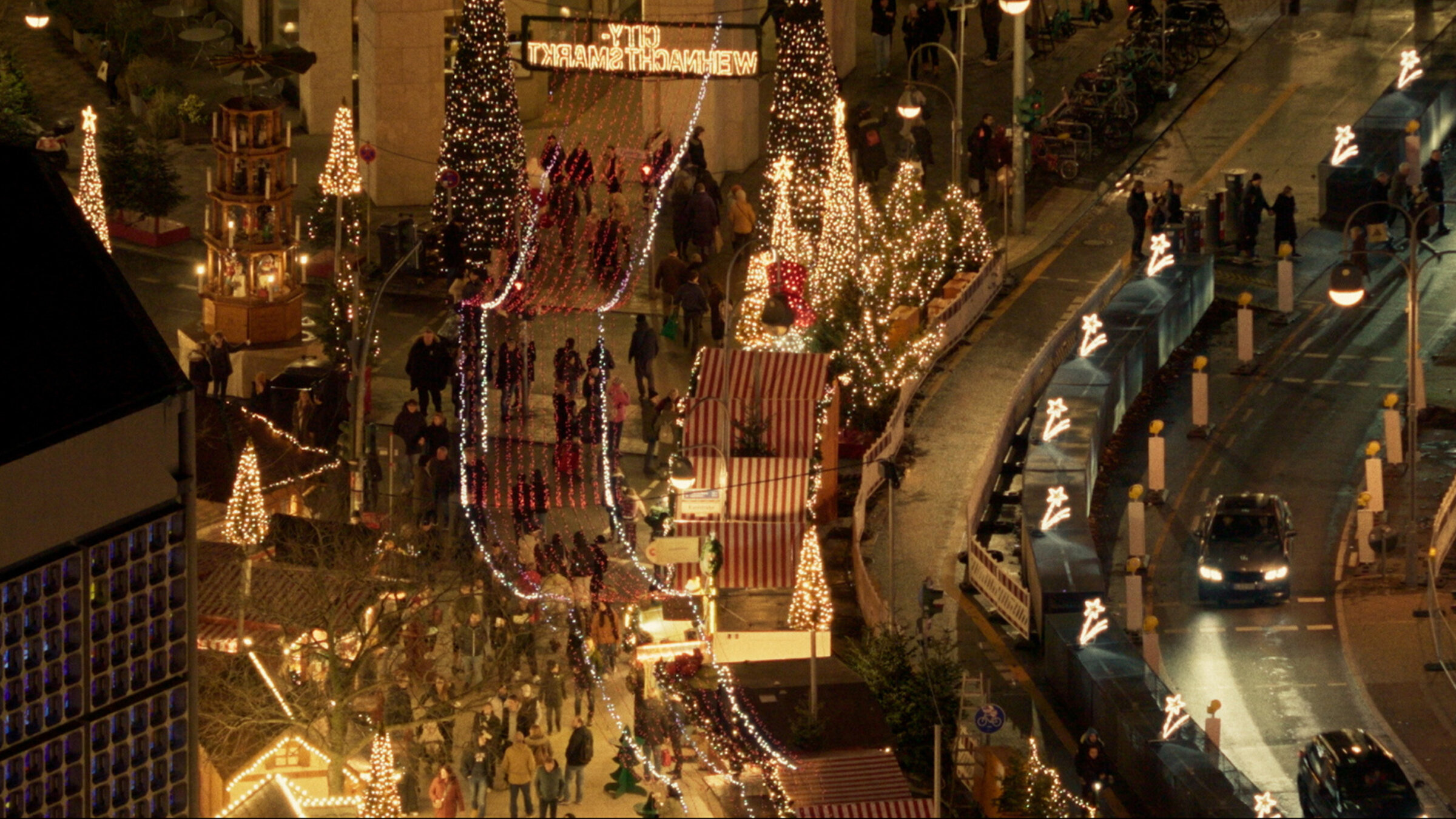 "Der Anschlag": Totale von weihnachtlich geschmückten Buden und Lichterketten.