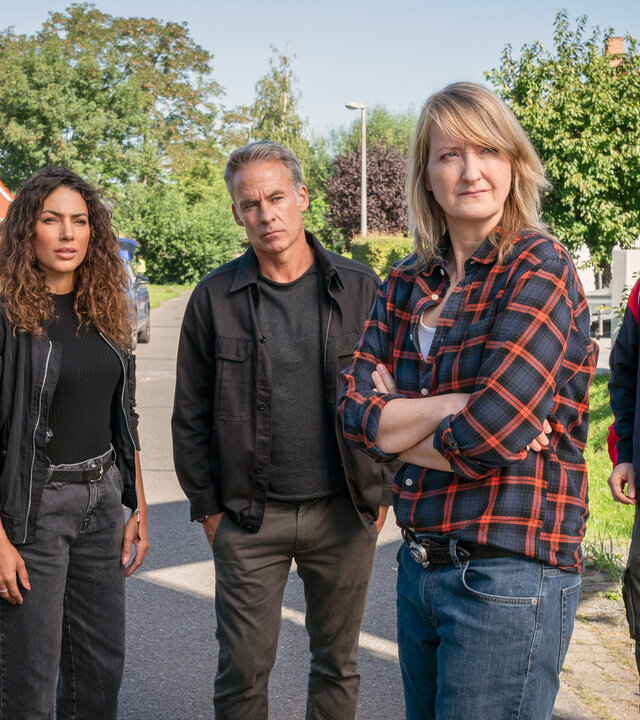 "SOKO Leipzig - Hasch mich": Kim (Amy Mußul), Jan (Marco Girnth), Wolfgang Güntgen (Michael Benthin) und Silke Wegener (Annedore Kleist) stehen in einem gepflegten Wohngebiet auf einer Straße. Jimmy Niehaus (Michael Kranz) steht mit beunruhigtem Blick neben der Gruppe.