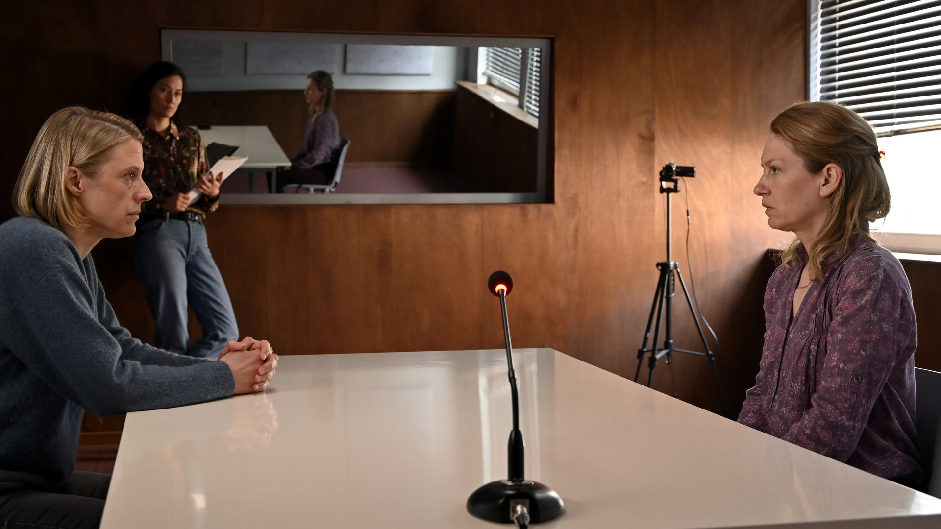 "SOKO Potsdam - Tödlicher Sonnenschein": An einem Verhörtisch sitzen sich Claire Hoffmann (Anna Blomeier) und Kommissarin Tamara Meurer (Anja Pahl)  gegenüber. Im Hintergrund mit einem Notizblock in der Hand steht Kommissarin Pauline Hobrecht (Agnes Decker) .