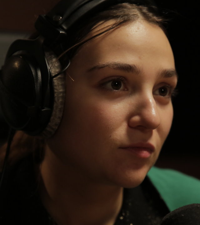 "About Saturday - Samstag": Klara (Darin Hagi) sitzt in einem dunklen Tonstudio und schaut bedrückt in die Ferne, während sie Kopfhörer trägt.