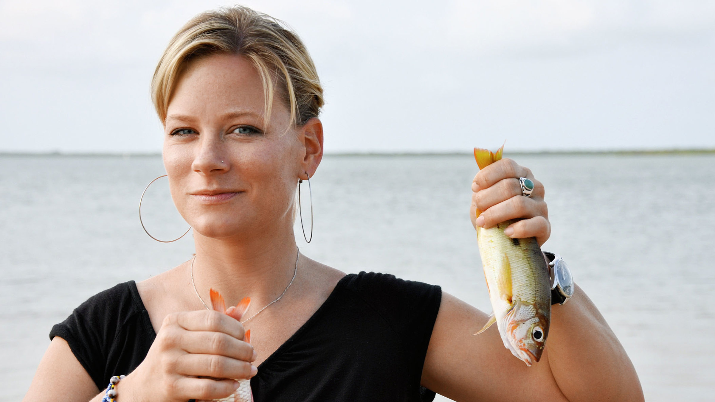 "unterwegs - Kenia": Moderatorin Andrea Jansen in Kenia am Strand. Sie hält in jeder Hand einen Fisch.