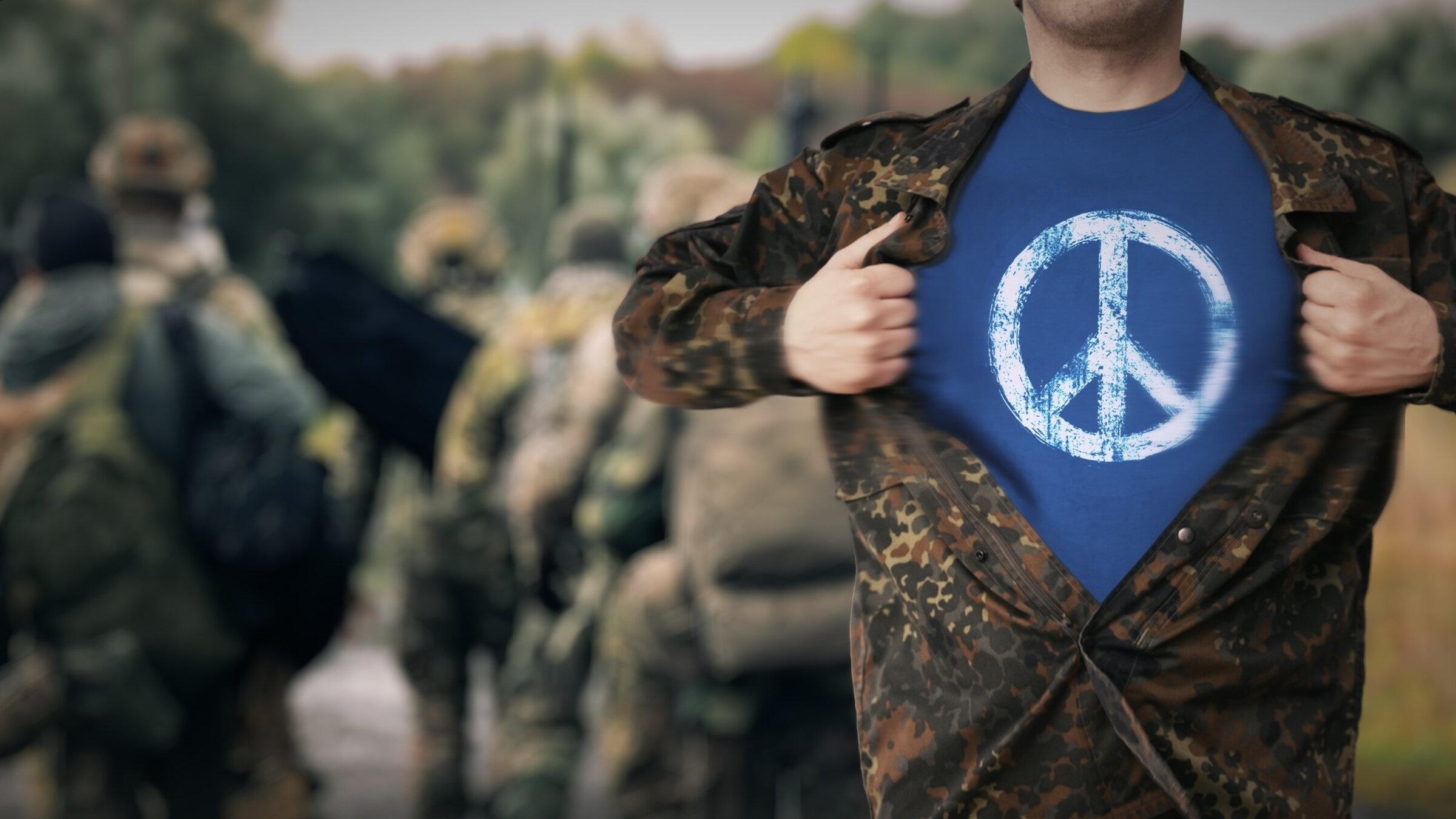 "Eine Frage des Gewissens": Ein Mann in Flecktarn reiÃt seine Jacke auf und trÃ¤gt darunter ein T-Shirt mit einem Peace-Zeichen.