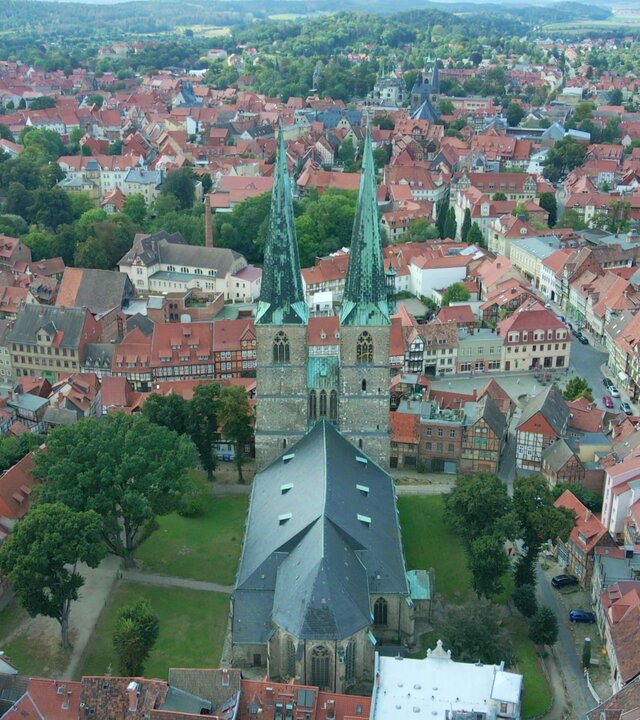 "Evangelischer Gottesdienst - Der andere Blick": Luftbild der evangelischen Kirche St. Nikolai mit ihren beiden schlanken, hoch aufragenden Türmen, die inmitten der Altstadt von Quedlinburg steht.