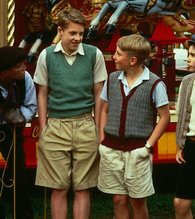 "Fünf Freunde jagen die Entführer": Spikey (Lee Barrett), Julian (Marco Williamson), Dick (Paul Child) und Jo (Vanessa Cavanagh) stehen nebeneinander vor einem Kinderkarussell und blicken sich nachdenklich an.