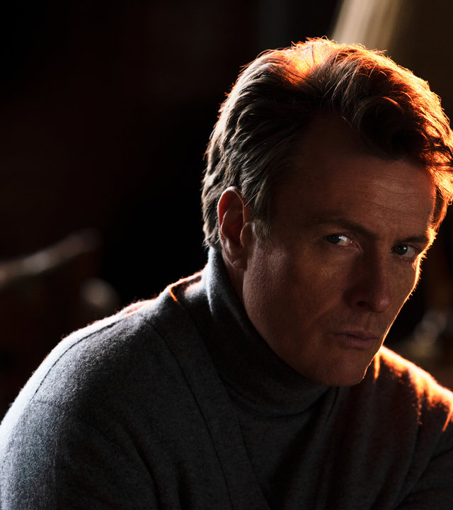 "Alex Rider - Überfall": Cray (Toby Stephens) sitzt in einem Zimmer und schaut angespannt in die Ferne.