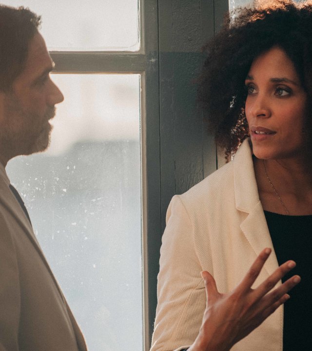 "Survivors - Malika": Stefano (Fausto Sciarappa) und Sylvie (Stéfi Celma) stehen sich vor einer Fensterfront gegenüber und unterhalten sich.