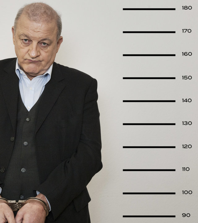 "Wilsberg – Kein Weg zurück": Ein Gefängnis-Portrait von Georg Wilsberg (Leonard Lansink), der in Handschellen neben einer Messlatte steht.