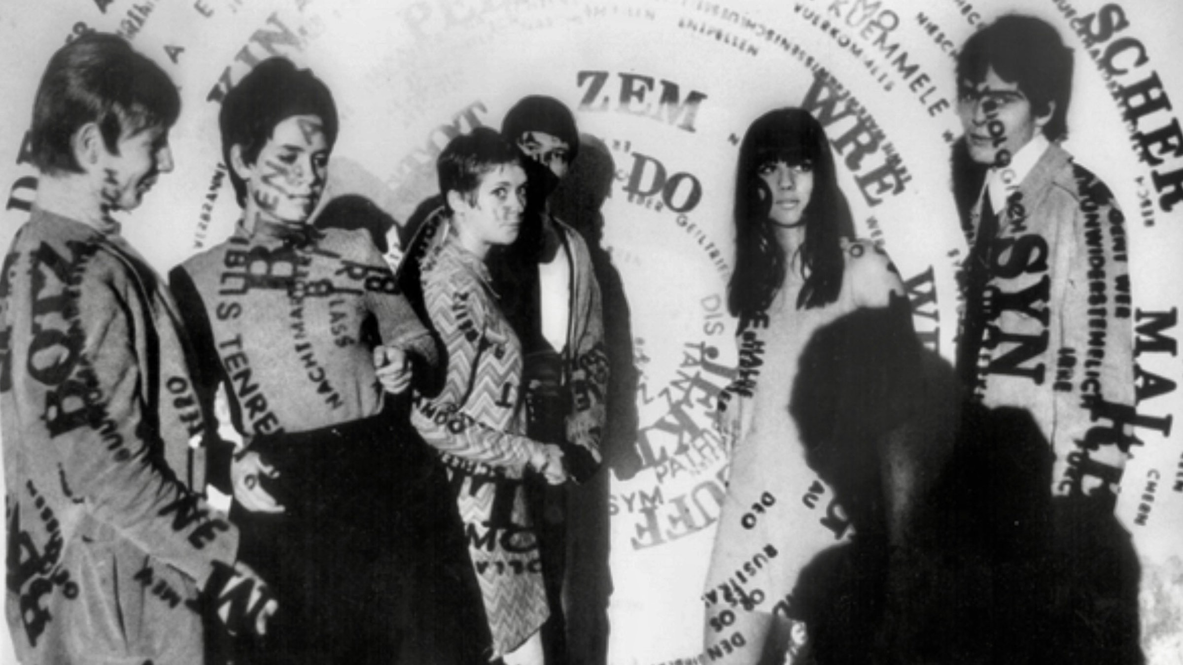 "Radical Disco - Die frühen Jahre der Clubs": Eine Wortspirale wird als Lichtprojektion  auf junge tanzende Menschen geworfen, auf Ihren Körpern ist die Schrift zu lesen, ein Schwarz/Weißfoto.