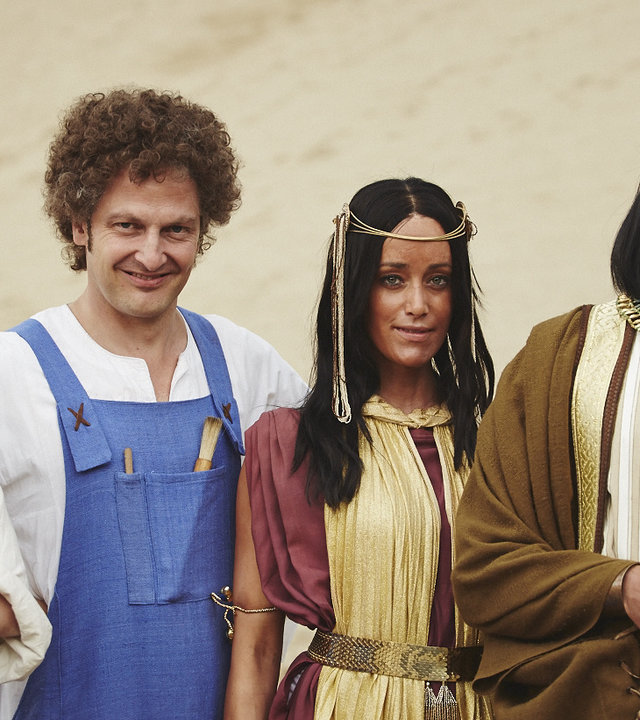 Alexander Schubert und Holger Stockhaus stehen als Bauunternehmer in blauen Togas verkleidet neben Judith Richter und Max Giermann, die in Gewänder des alten Ägypten gehüllt sind. Sie stehen in der Wüste und schauen direkt in die Kamera.