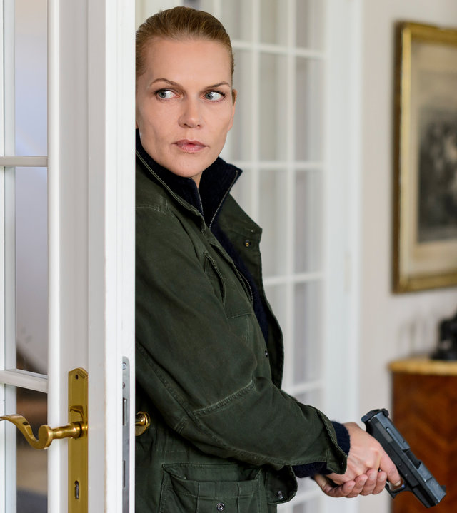 "Helen Dorn - Schatten der Vergangenheit": Helen Dorn (Anna Loos) lehnt an einer Tür und hält eine Pistole in der Hand.