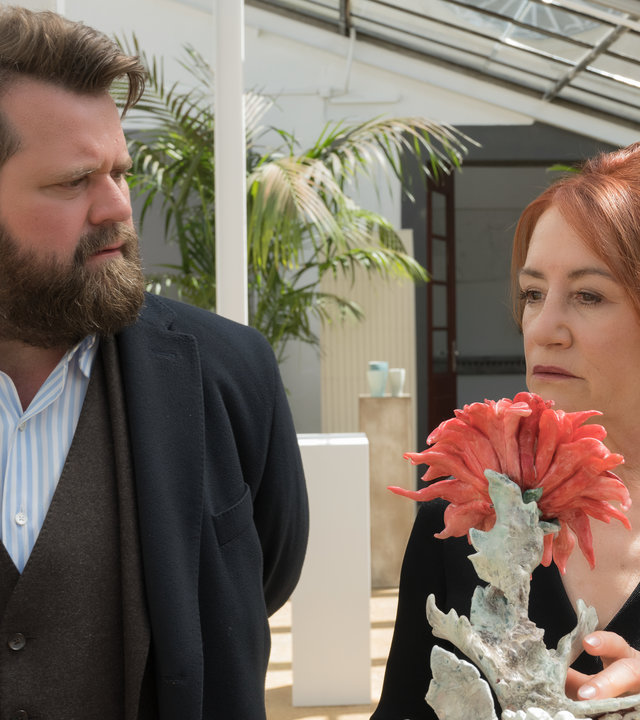 "Ein Fall für zwei - In Liebe W.": Benni Hornberg (Antoine Monot, Jr.) steht mit Marianne Geiger (Ulrike Krumbiegel) im Ausstellungsraum, der sich in einem Wintergarten befindet. Vor ihnen steht eine Skulptur einer Dahlie. Die beiden unterhalten sich.
