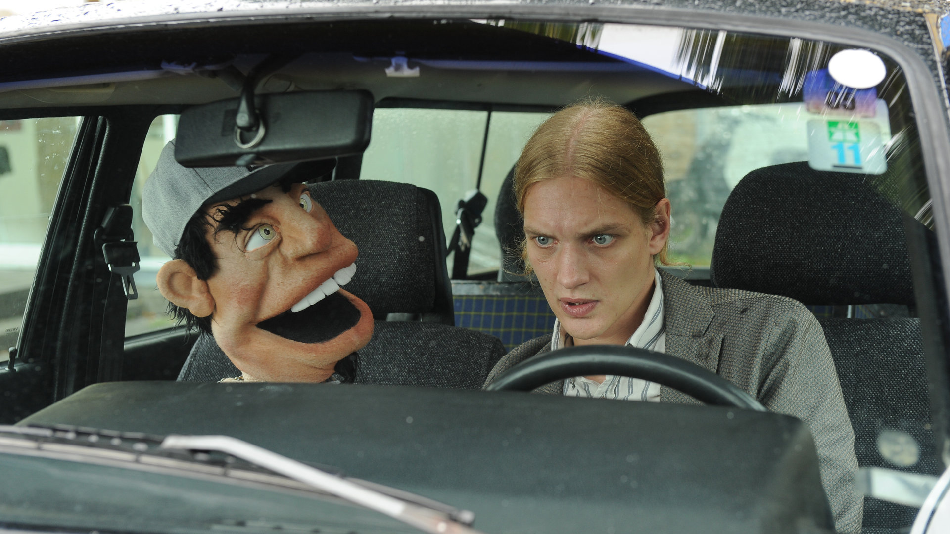 "SOKO Stuttgart - Bauchgefühle": Simon Janetski (Paul Boche) sitzt am Steuer eines Autos. Neben ihm seine Bauchrednerpuppe Herbert.