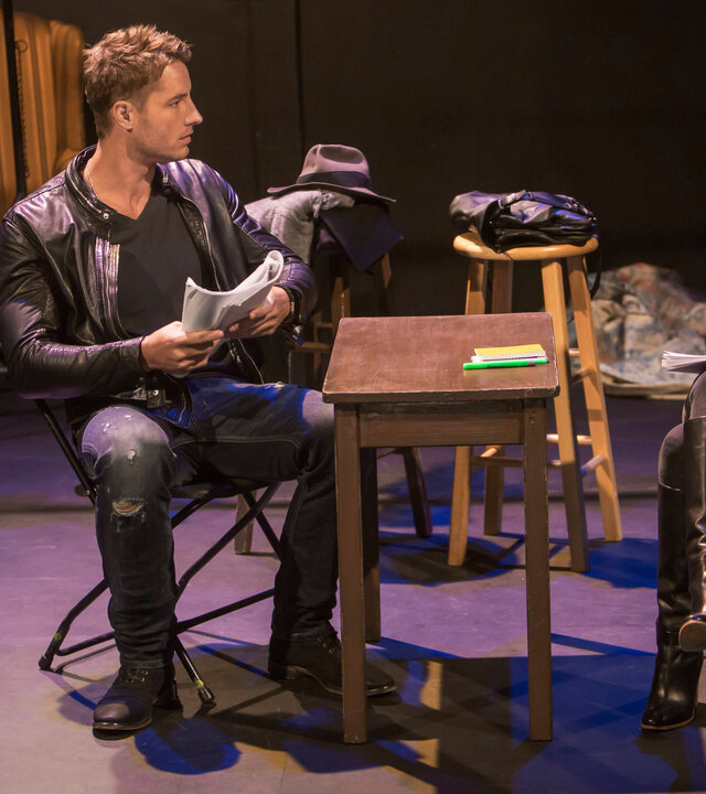 "This Is Us - Das ist Leben: Das magische T-Shirt": Kevin Pearson (Justin Hartley) und Olivia Maine (Janet Montgomery) sitzen sich auf einer Theaterbühne an einem schmalen Tisch gegenüber. Kevin hält ein Skript in den Händen und blickt Olivia fragend an. Olivia hält ebenfalls ein Skript in den Händen und blickt zu Kevin.