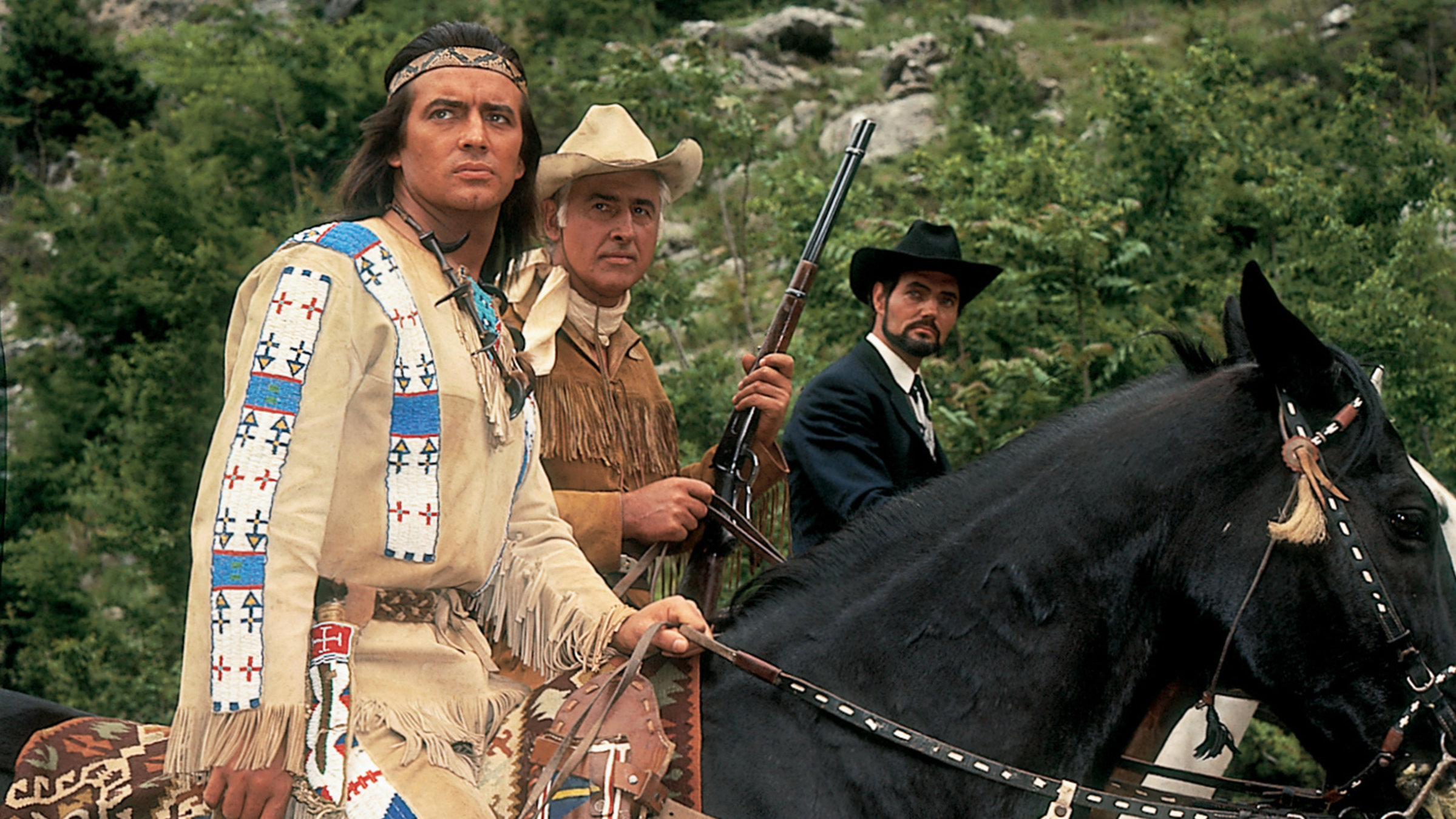 "Der Ölprinz": Winnetou (Pierre Brice), Old Surehand (Stewart Granger) und der Ölprinz (Harald Leipnitz) reiten nebeneinander und schauen in die gleiche Richtung.