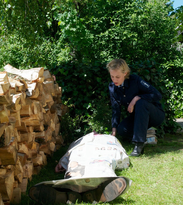 "SOKO Wismar - Bankgeheimnis": Neben einer Brennholzreihe in einem Garten kniet Leena Virtanen (Li Hagman) neben einer zugedeckten Leiche.