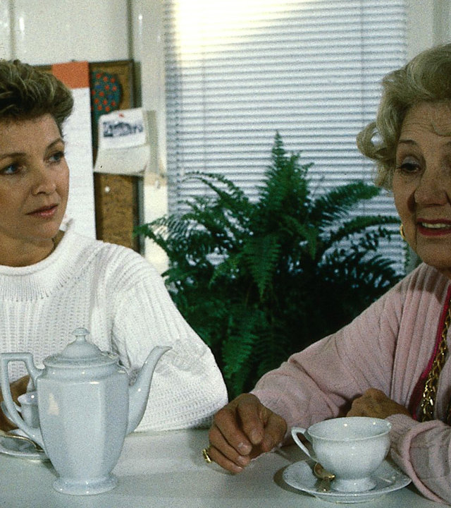 "Der Landarzt - Der Kräuterdoktor": Annemarie (Gila von Weitershausen) und ihre Mutter (Jane Tilden) trinken zusammen eine Tasse Kaffee. Annemarie schaut zu ihrer Mutter, die wiederum unzufrieden ins Leere schaut.