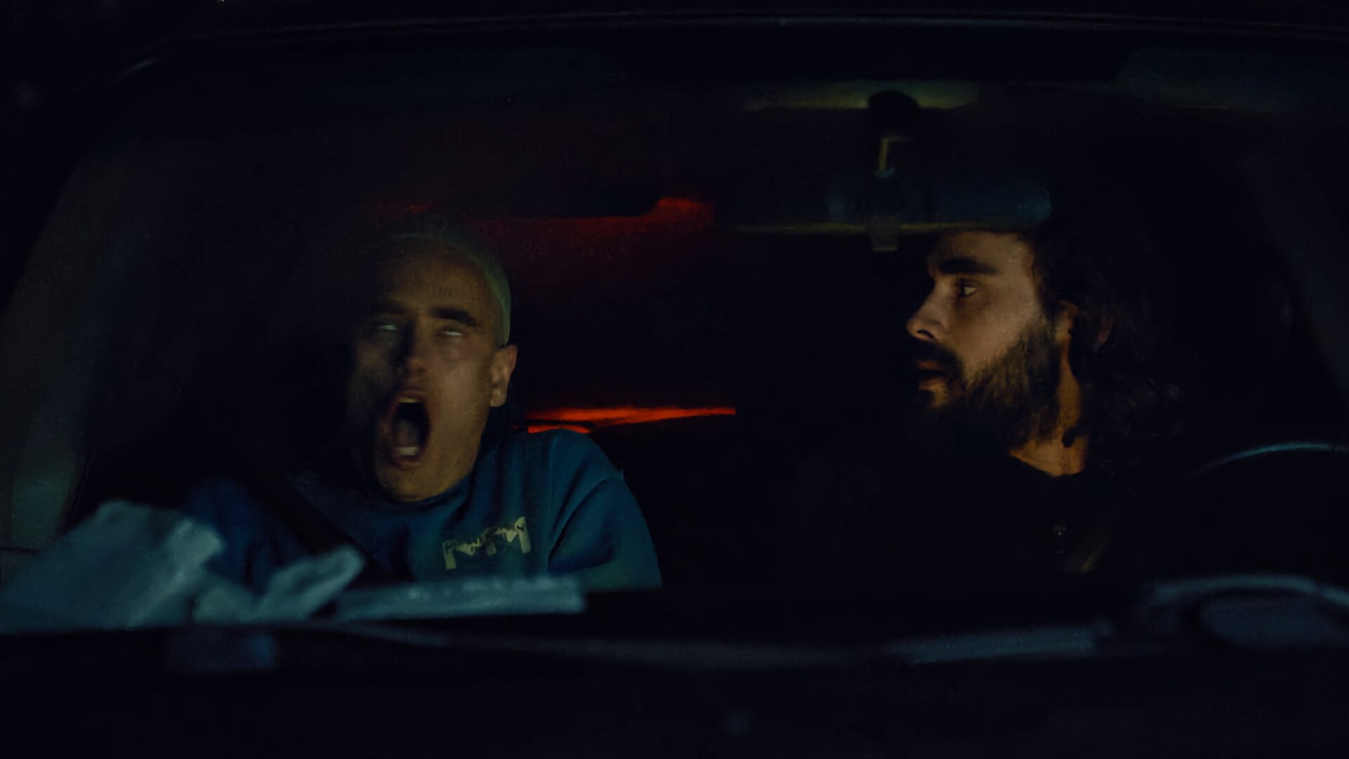 "Moresnet - The Book of Death: Ich bin nicht ich": Daan Schotz (Arend Pinoy) sitzt nachts auf dem Beifahrersitz eines Autos. Sein Mund ist aufgerissen, die Augen schauen nach oben unter die Augenlider - er hat einen Anfall. Sein Bruder Ben Schotz (Boris Van Severen) blickt sorgenvoll vom Fahrersitz zu ihm herüber.