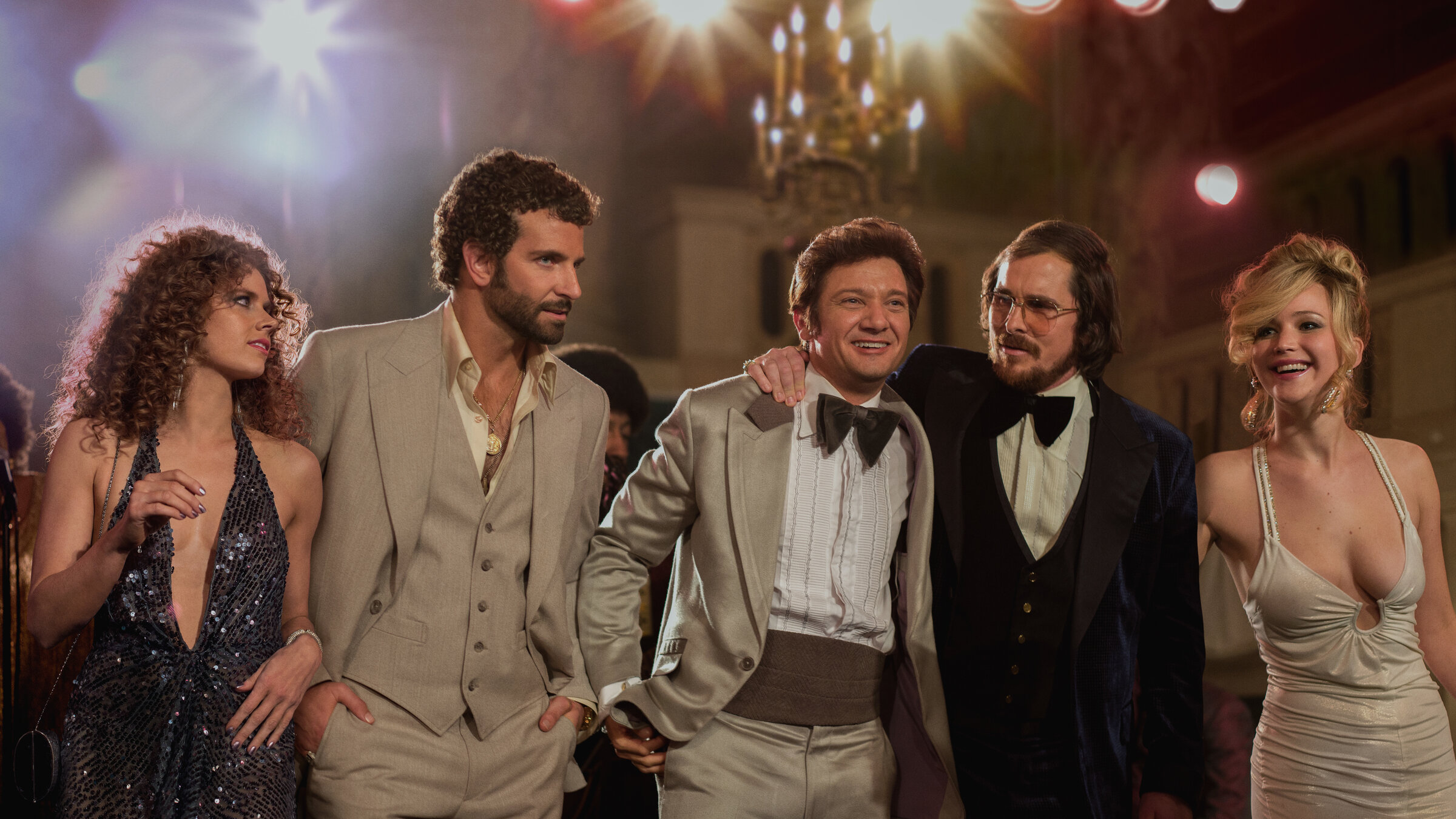 "American Hustle": Sydney (Amy Adams), Agent DiMaso (Bradley Cooper), Bürgermeister Polito (Jeremy Renner), Irving (Christian Bale) und Noch-Ehefrau Rosalyn (Jennifer Lawrence) stehen in Abendkleidung nebeneinander.