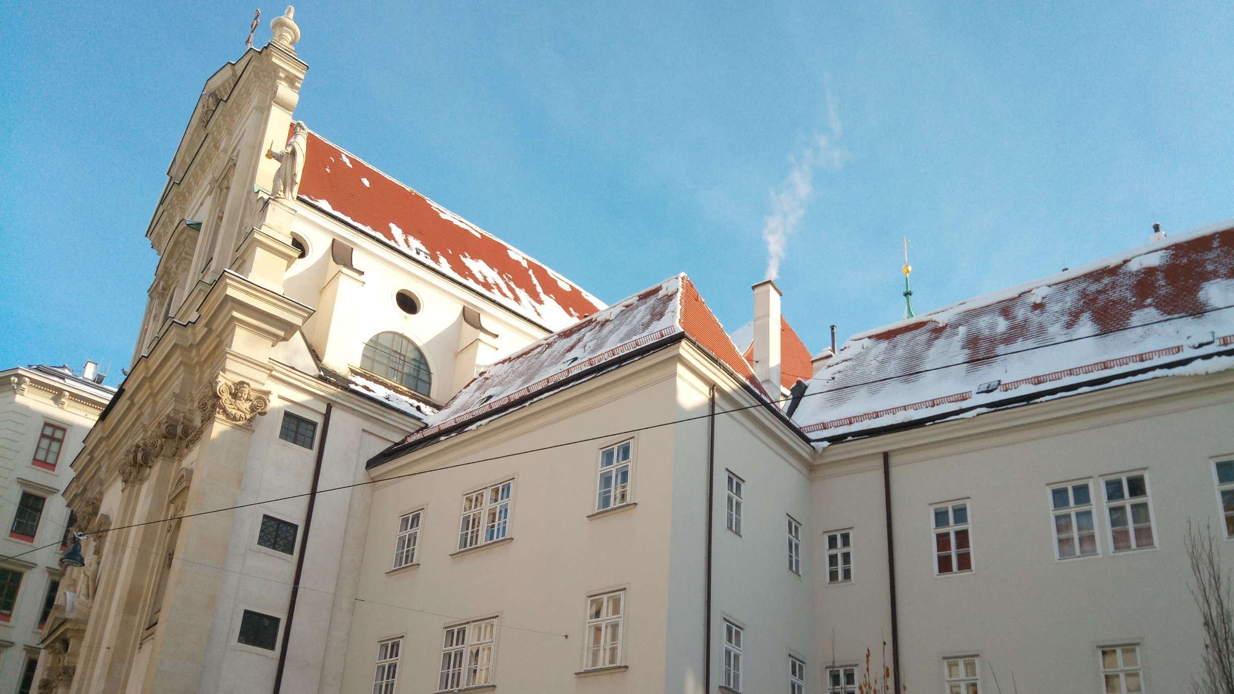"Katholischer Gottesdienst - Mach dich auf den Weg": Außenansicht der Dominikanerkirche Wien mit Kloster im Winter. Die Dächer sind leicht schneebedeckt.