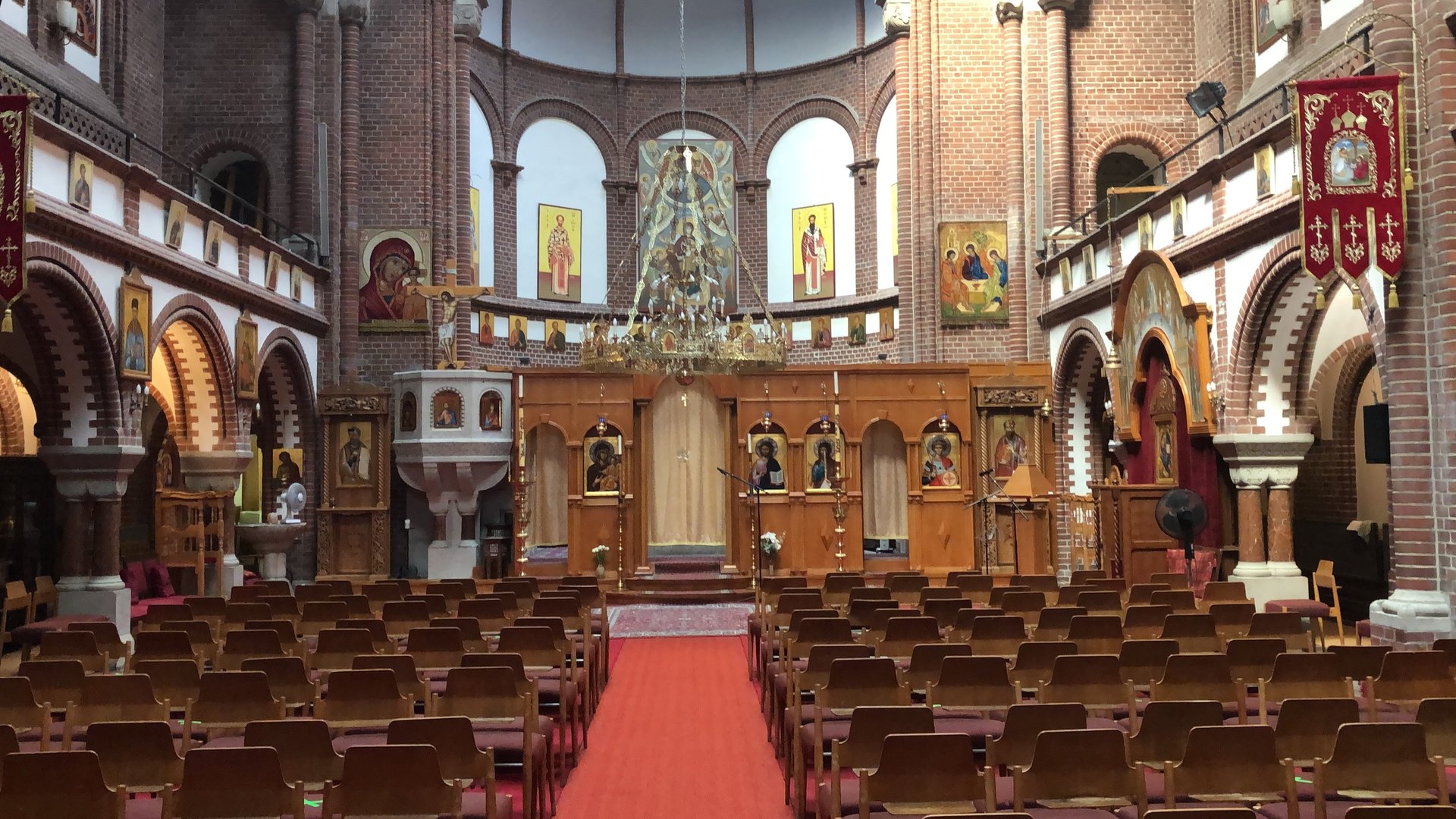 "Orthodoxer Gottesdienst - Gottes Gnade genügt": Blick in den Kirchenraum auf die Ikonostase, die Wände sind mit Ikonen behängt.
