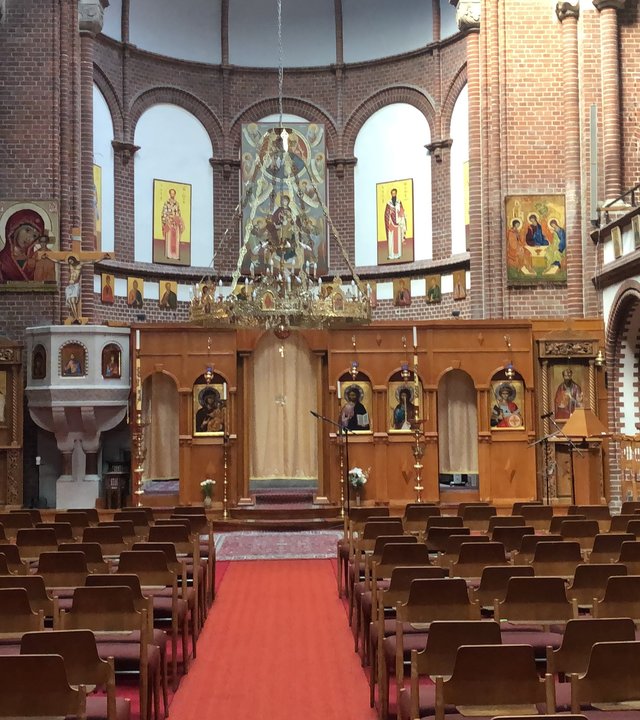 "Orthodoxer Gottesdienst - Gottes Gnade genügt": Blick in den Kirchenraum auf die Ikonostase, die Wände sind mit Ikonen behängt.