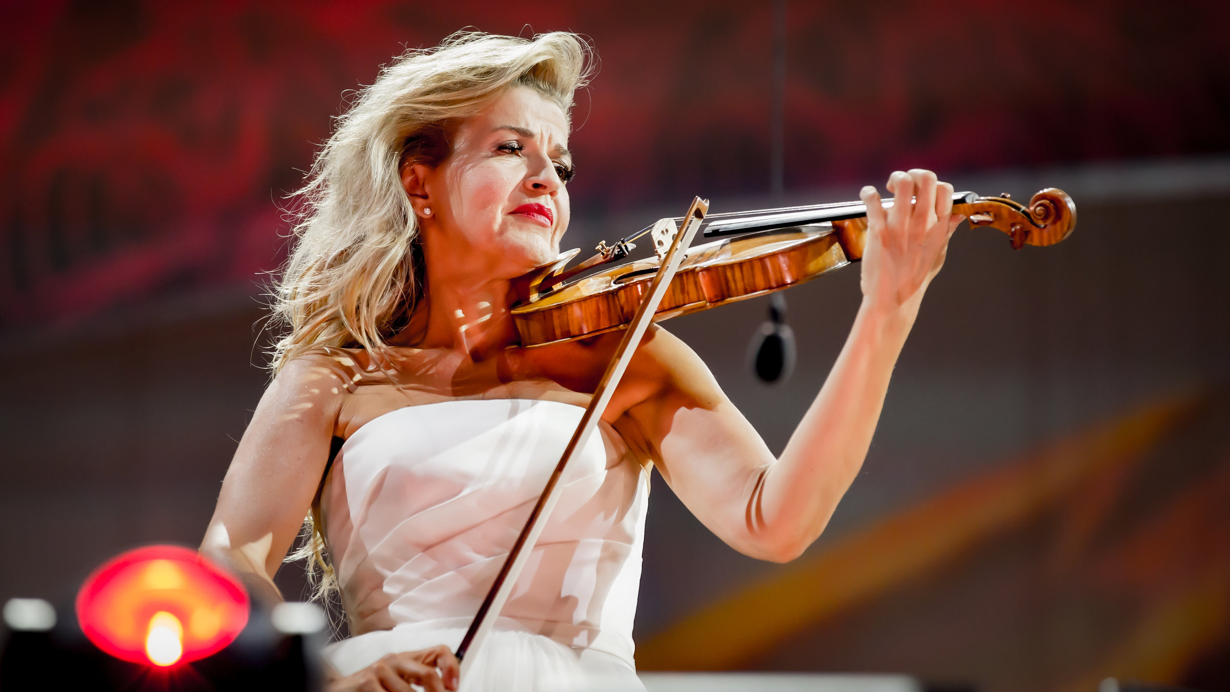 "Anne-Sophie Mutter spielt Filmmusik": Anne-Sophie Mutter steht im weißen schulterfreien Kleid mit ihrer Violine auf der Bühne und spielt.