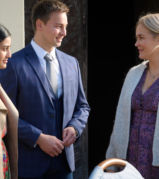 "Lena Lorenz - Überväter": Vor einer Kirchentür stehen Greta (Sogol Faghani) und Ferdinand Junghans (Timmi Trinks) mit einem Kinderwagen und unterhalten sich mit Lena Lorenz (Judith Hoersch), die ihren kleinen Sohn Luis (Samuel Gerbrich) an der Hand hält.
