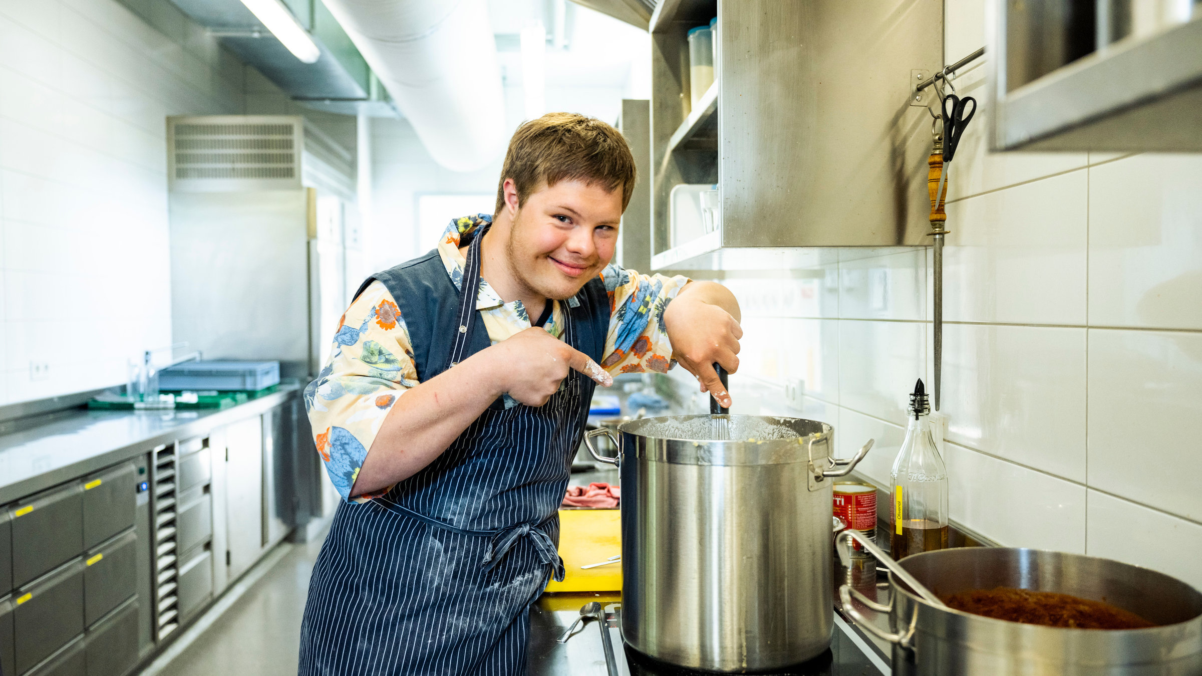"Einfach Mensch! - Ein Job für mich!": Der perfekte Job für mich" Florian Grollmus steht am Herd vor einem großen silbernen Kochtopf.