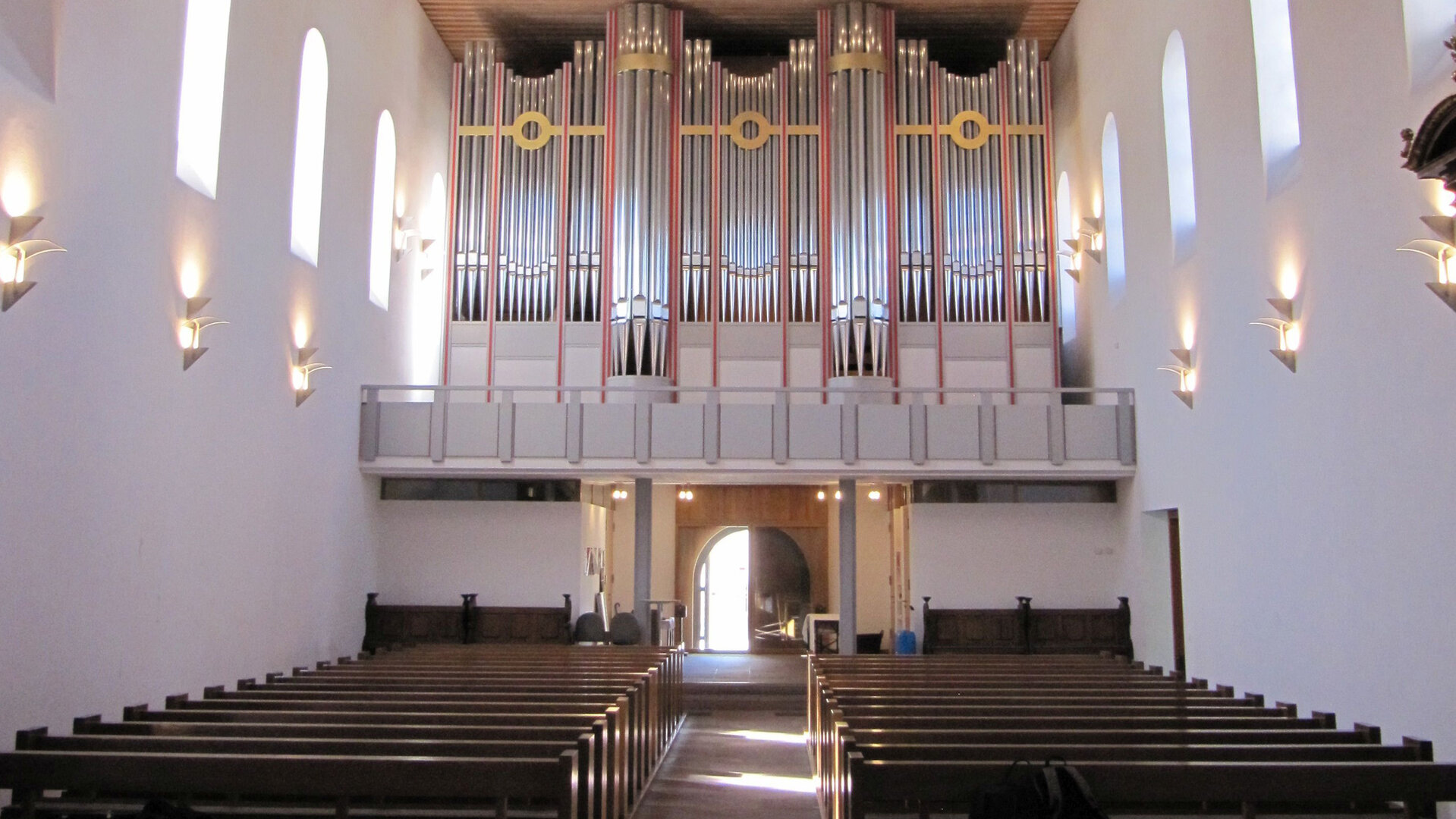 "Evangelischer Gottesdienst - Dich schickt der Himmel": Blick in den Innenraum der Ingelheimer Saalkirche mit der beeindruckenden Orgel. Durch die Fenster links und rechts der Orgel scheint die Sonne. Die dunkelbraunen Holzbänke heben sich von den weißen Wänden in der lichtdurchfluteten Kirche ab.
