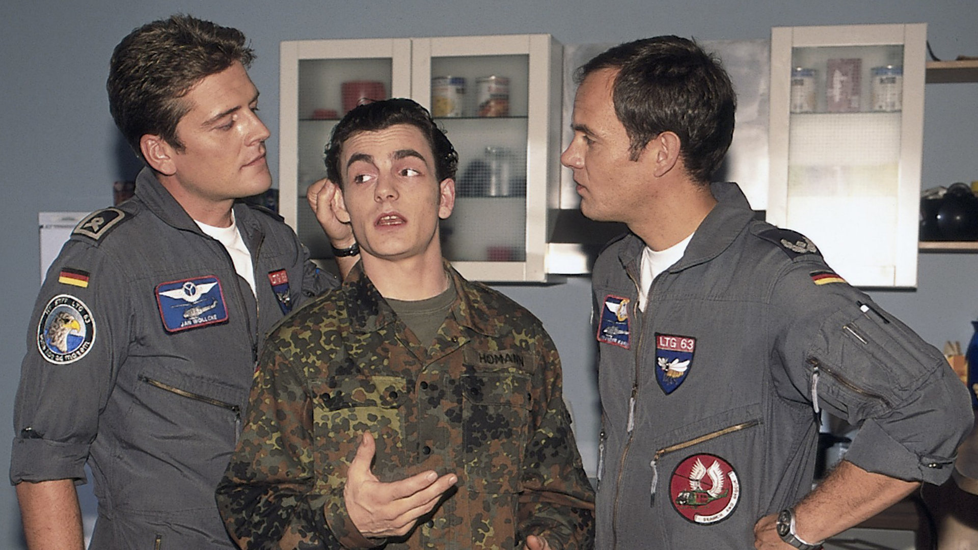 "Die Rettungsflieger - Gerüchteküche": Wollcke (Oliver Hörner), Alex (Matthias Leja) und Homann (Pierre René Müller) stehen nebeneinander. Wollcke zieht Homann am Ohr.
